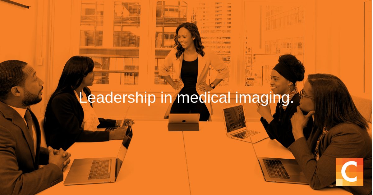 In orange preset - 5 workers at table for meeting with leader standing at head of table - with text "Leadership is Medical Imaging"