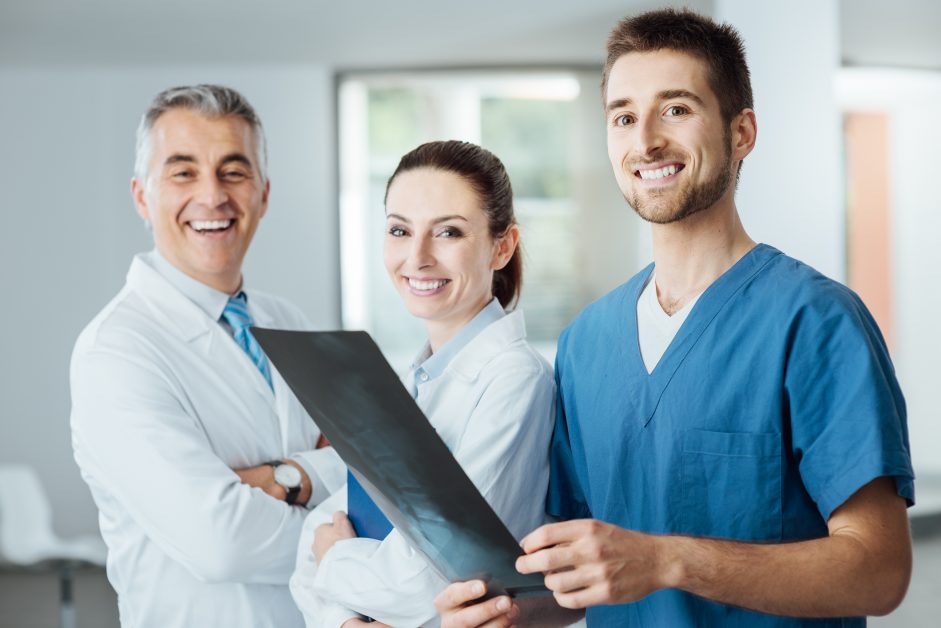 imagem de radiologistas sorrindo para a câmera e segurando um filme de raio-x
