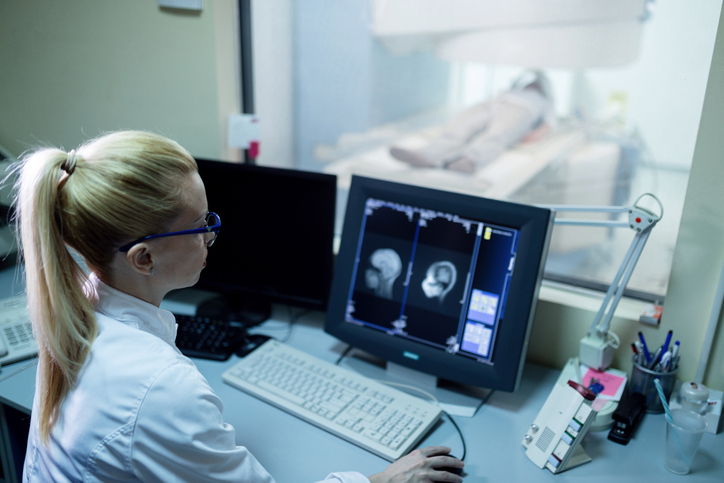 Doctora analizando los resultados de la exploración de resonancia magnética del cerebro de un paciente en el monitor de la computadora en la sala de control.